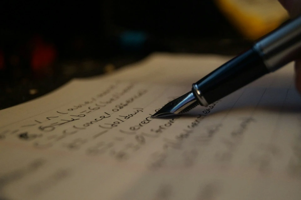 a person writing on a piece of paper with a pen